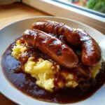 Three browned sausages served over creamy mashed potatoes, smothered in rich onion gravy for classic bangers and mash.