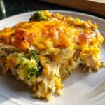 A close-up of a serving of cheesy chicken and broccoli rice casserole with a golden brown topping.