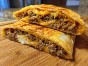 Close-up of cheesy pocket tacos cut in half, revealing a gooey filling of seasoned ground beef and melted cheddar cheese.