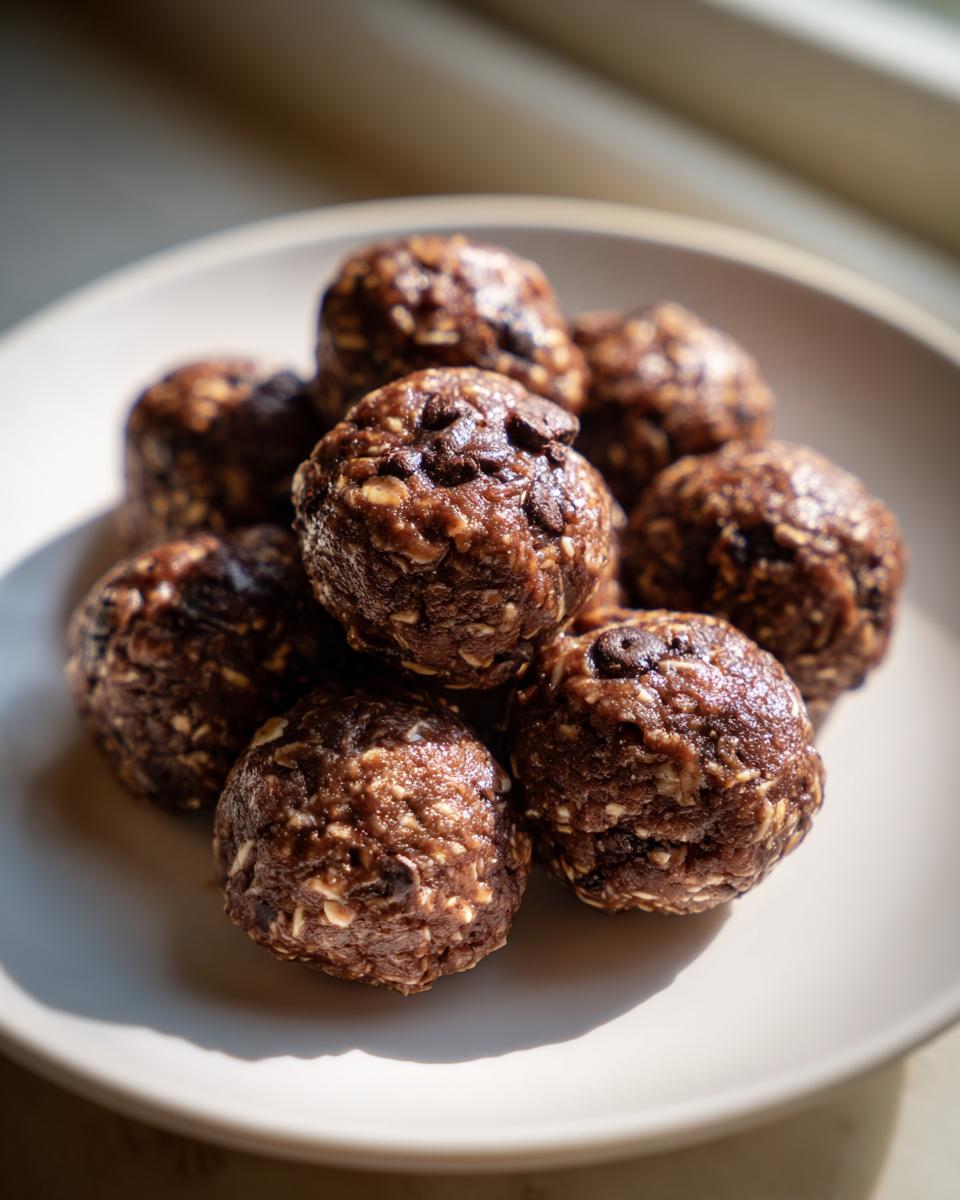 A close-up stack of homemade chocolate chip protein balls resting on a light-colored plate.