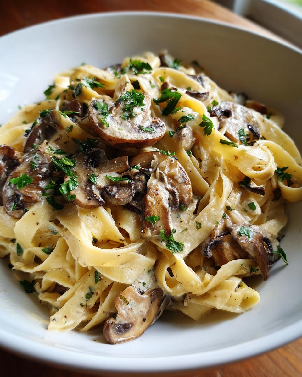 Close-up of creamy fettuccine noodles mixed with sautéed mushrooms and fresh parsley, showcasing the amazing 1-pot mushroom pasta.