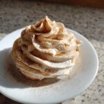 A mound of fluffy, piped topping, likely cinnamon butter, dusted heavily with cinnamon powder.
