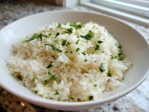 A close-up of fluffy white rice seasoned with butter and topped with fresh parsley, representing delicious garlic butter rice.