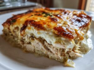 Close-up of a serving of green chile chicken enchiladas with shredded chicken and melted, browned cheese topping.