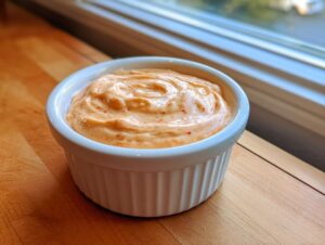 A close-up of creamy, orange-hued homemade Big Mac Sauce swirled in a small white ramekin.