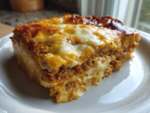 A close-up of a rich, cheesy slice of homemade Reuben bake served on a white plate.