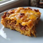 A close-up of a cheesy slice of homemade Reuben bake with corned beef and sauerkraut.