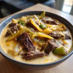 Close-up of a hearty bowl of philly cheese steak soup, featuring chunks of steak, melted cheese, and peppers in a creamy broth.