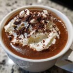 Close-up of rich boozy hot chocolate topped with whipped cream and dark chocolate shavings.