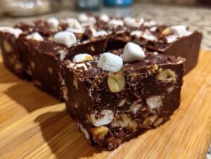 A close-up view of rich, dark chocolate rocky road fudge squares loaded with nuts and marshmallows.