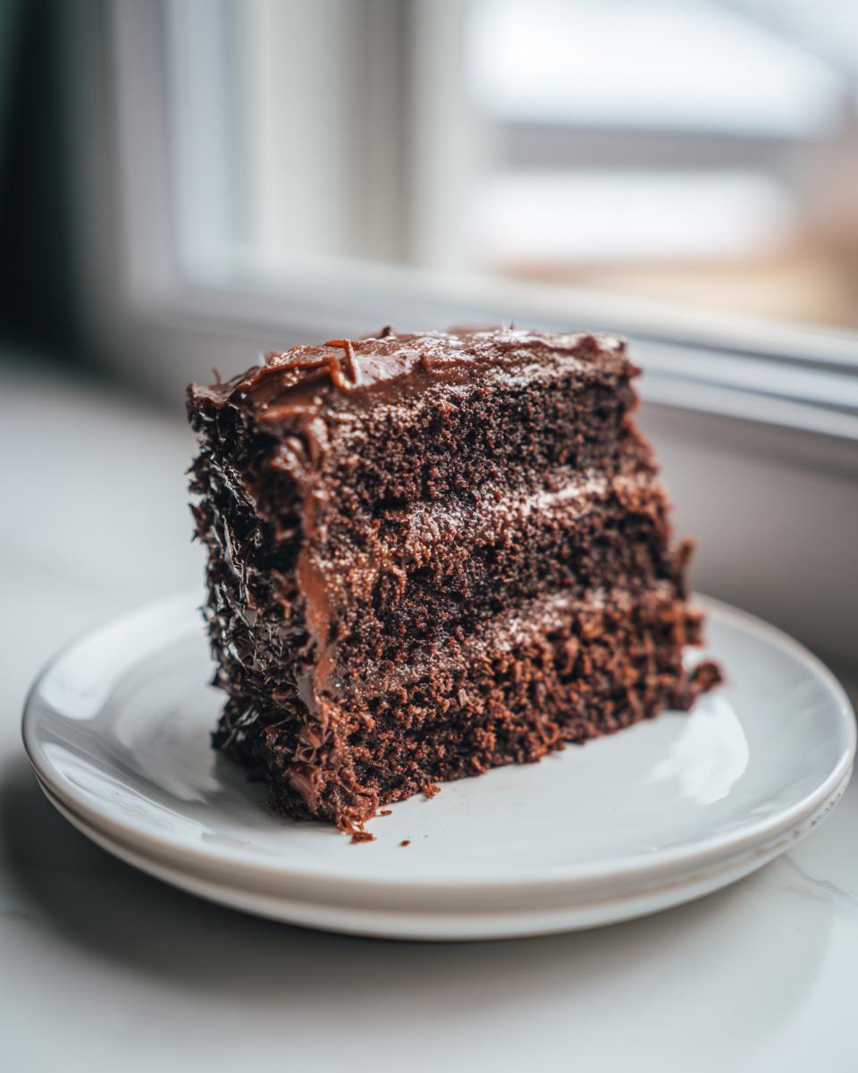 A decadent slice of dark, multi-layered chocolate cake served on a white plate, referencing the german chocolate cake recipe.