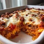 Close-up of a hearty baked casserole featuring layers of meat sauce, melted cheese, and what appears to be shredded cabbage in this cabbage recipe.