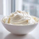 A white bowl filled with freshly whipped, smooth, and creamy sugar cookie icing.