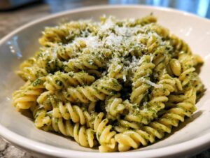 Close-up of creamy pesto pasta made with fusilli, topped with grated Parmesan cheese.