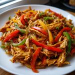 Close-up of shredded chicken mixed with colorful bell peppers and onions, ready for crockpot chicken fajitas.