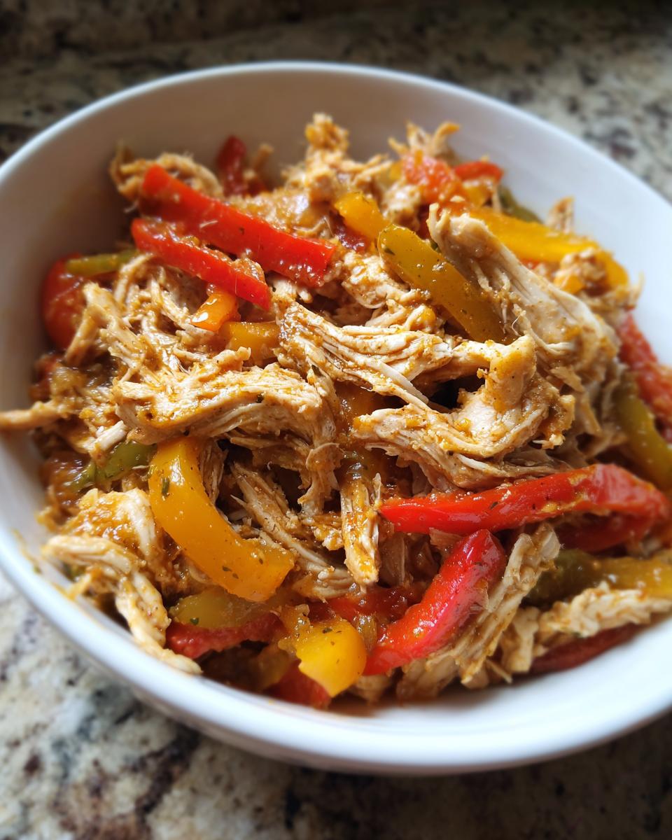 Close-up of shredded chicken mixed with colorful bell peppers, ready for crockpot chicken fajitas.