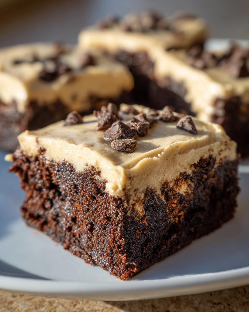 Close-up of a fudgy banana bread brownies square topped with light brown frosting and chocolate chunks.
