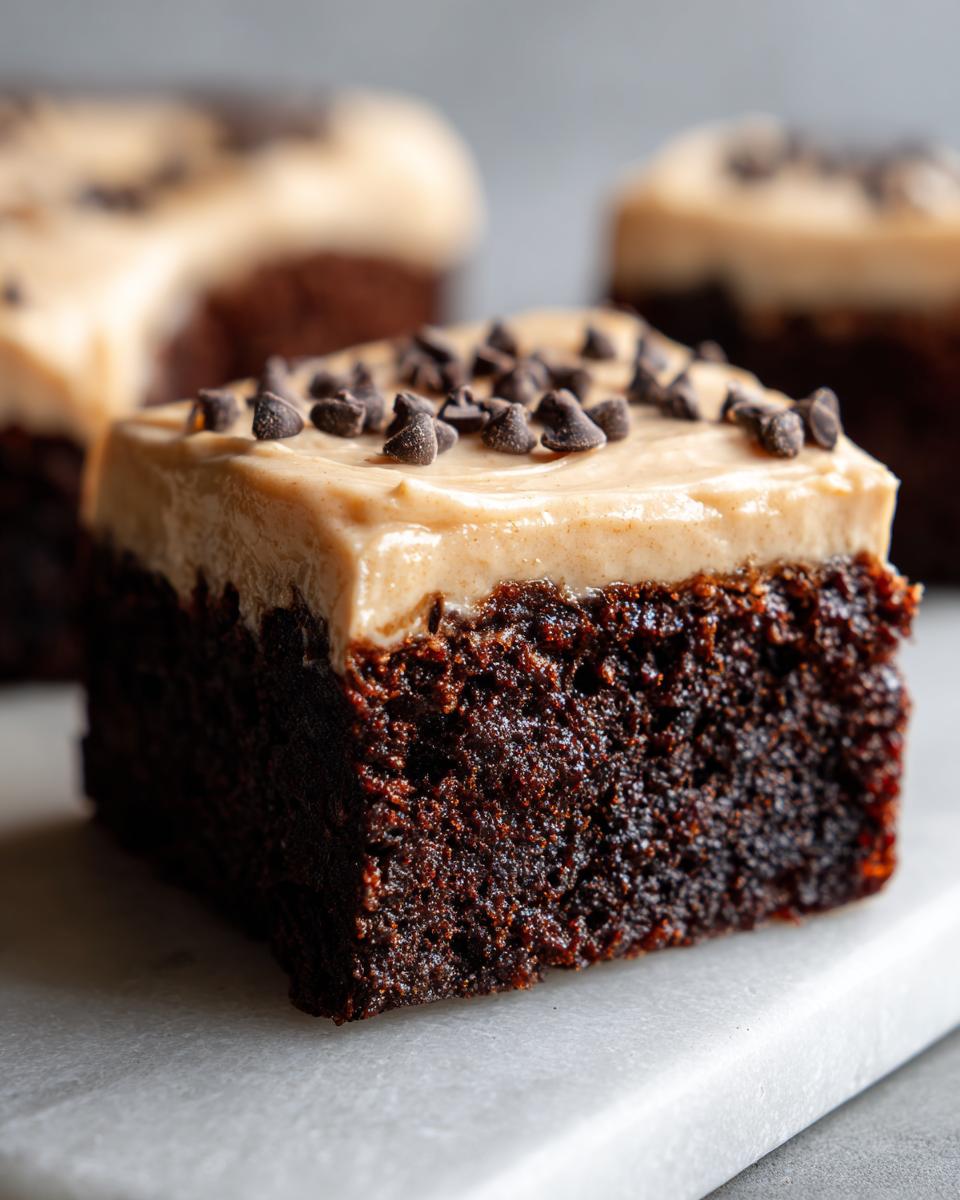 A close-up of a fudgy banana bread brownies square topped with peanut butter frosting and mini chocolate chips.