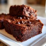 Close-up of a fudgy slice of sweet potato brownies topped with melted chocolate chips on a white plate.