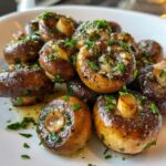 A close-up of perfectly cooked garlic butter mushrooms, glistening with sauce and topped with fresh chopped parsley.