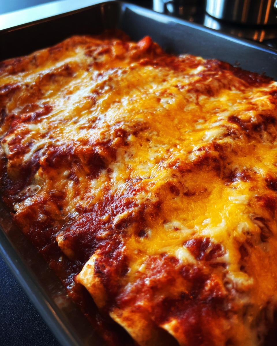 Close-up of freshly baked cheese enchiladas covered in bubbling red sauce and melted golden cheese.