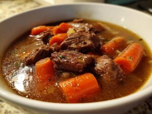 Close-up of a rich vegetable beef soup featuring large chunks of beef and bright orange carrots in a savory broth.