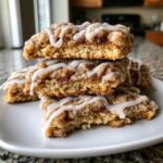 A stack of three delicious coffee cake cookies bars topped with cinnamon streusel and white icing drizzle.