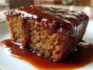 Close-up of a rich, moist slice of sticky toffee pudding recipe covered in glossy toffee sauce.