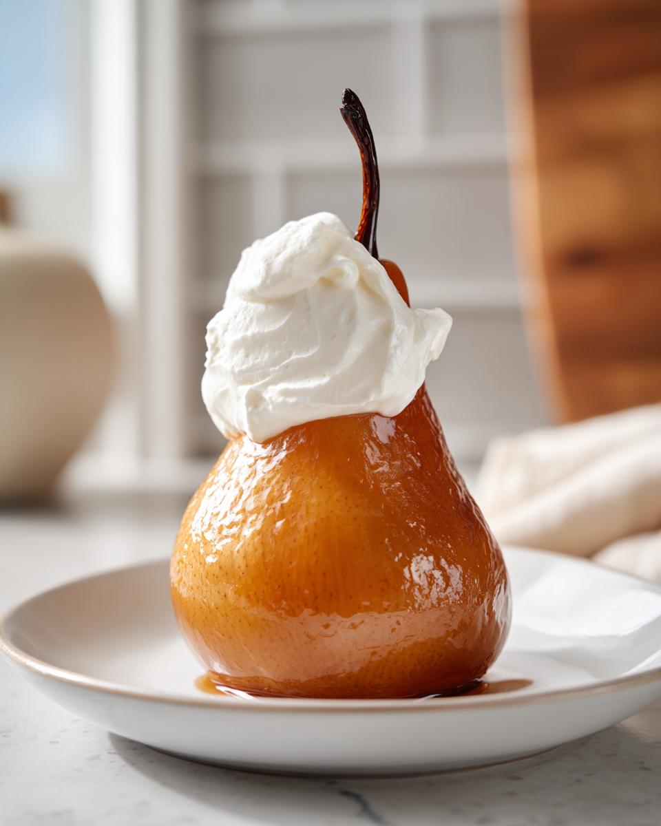 A single, beautifully glazed poached pear topped with a dollop of fresh whipped cream, served on a white plate.