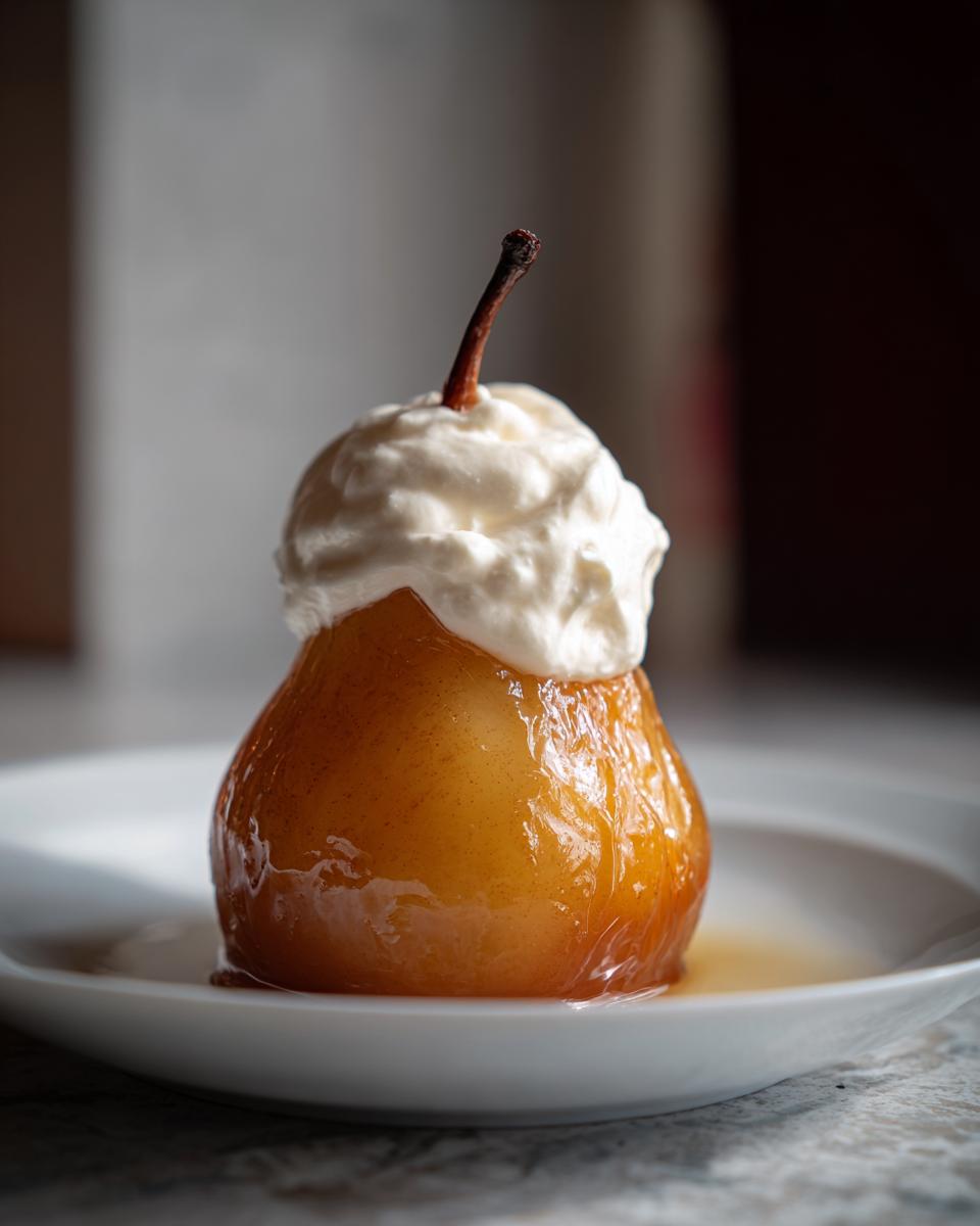 A beautifully glazed, amber-colored poached pear served in syrup and topped with a dollop of whipped cream.