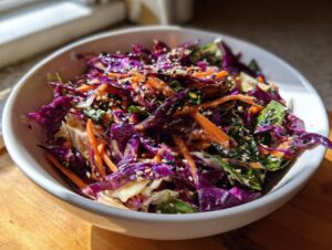 Close-up of a vibrant Asian cabbage salad featuring shredded purple cabbage, carrots, and topped with sesame seeds.