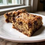 Two squares of rich, golden cake mix cookie bars studded with melted chocolate chips on a white plate.