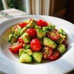 A vibrant close-up of homemade avocado salad featuring diced avocado and halved cherry tomatoes tossed in a light dressing.