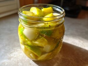 Close-up of sliced cucumbers and onions soaking in yellow brine for bread and butter pickle recipe.
