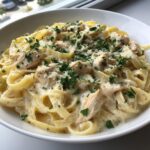 A close-up of creamy chicken fettuccine alfredo pasta topped with grated parmesan and fresh parsley.