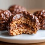 Close-up of a chocolate rice krispie balls with a bite taken out, showing gooey chocolate center.
