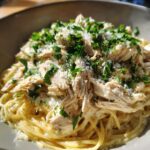 Shredded chicken from crock pot angel chicken served over creamy pasta, topped with Parmesan and parsley.
