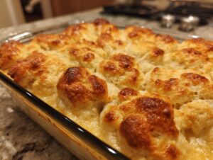 Close-up of a freshly baked pot pie casserole with golden brown biscuit topping bubbling in a glass dish.