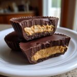 Close-up of two homemade peanut butter cups cut in half, showing thick chocolate shells and creamy peanut butter filling.