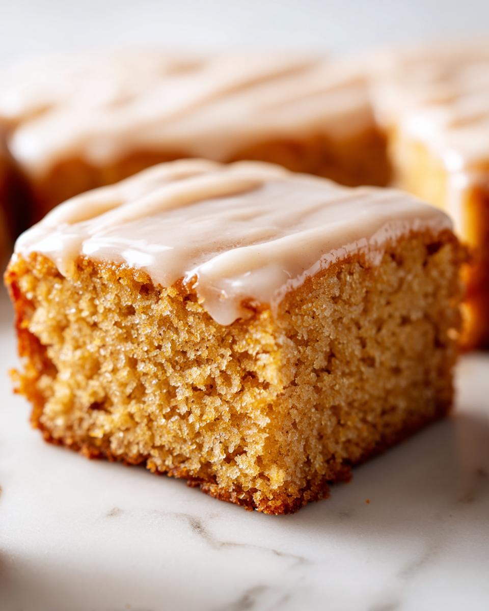 A close-up shot of a soft, square maple donut bars slice topped with a thick, creamy maple glaze.