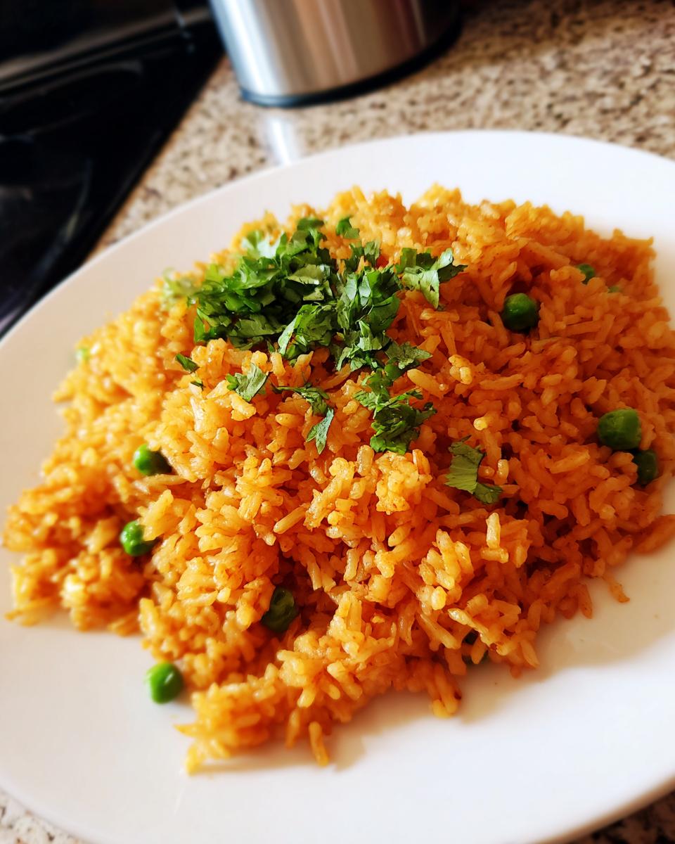 A plate of vibrant orange Mexican rice mixed with green peas and topped with fresh cilantro.