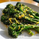 Close-up of perfectly roasted broccolini topped with bright yellow lemon zest and grated Parmesan cheese.