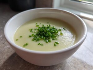 A creamy bowl of silky leek soup topped with freshly chopped green chives, ready to eat.