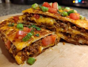 Two stacked slices of amazing mexican pizza showing melted cheese, seasoned ground beef filling, and fresh tomato and green onion toppings.