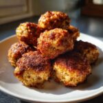 A close-up stack of golden brown, crispy stuffing balls piled high on a white plate.